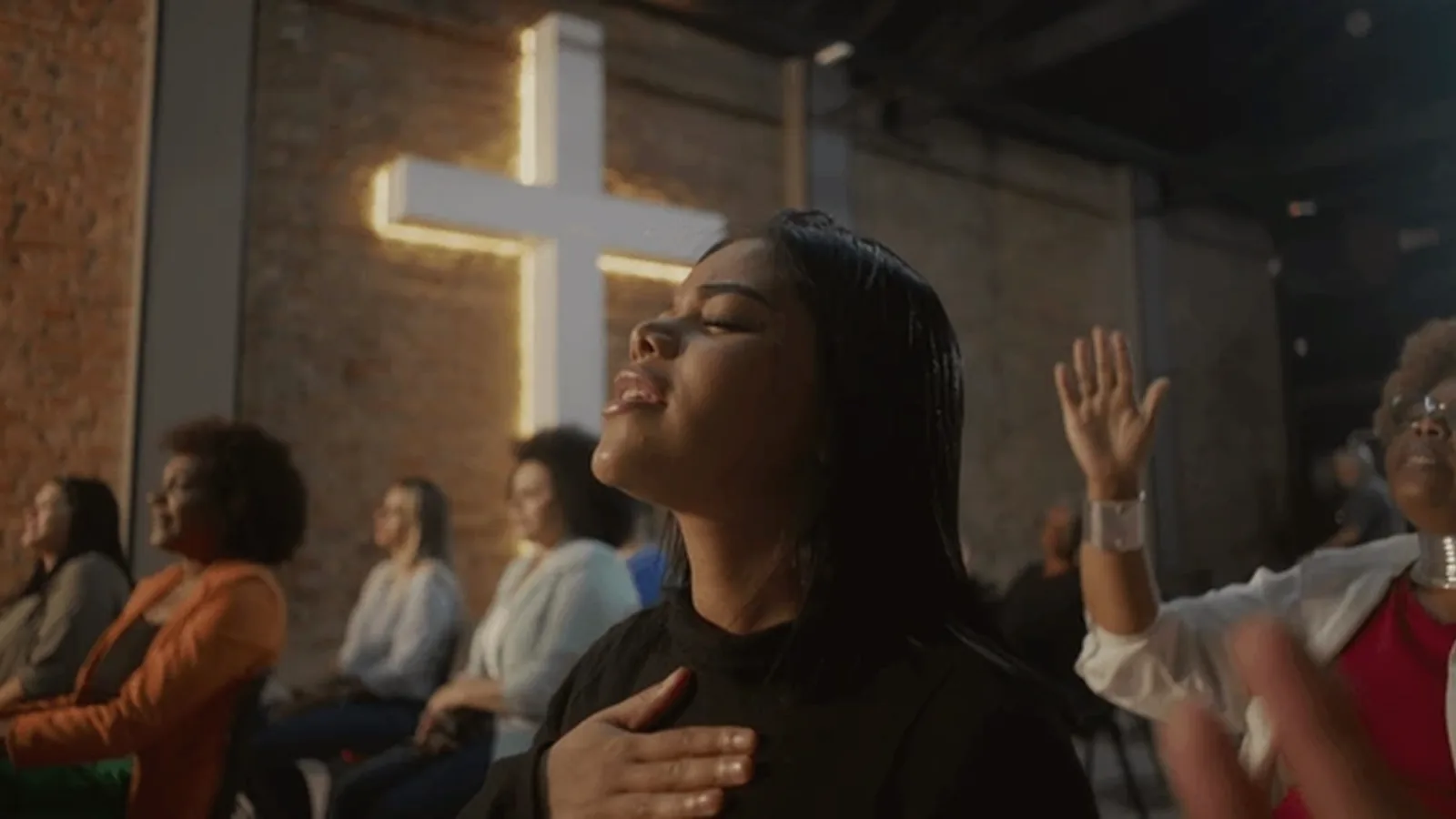 Women in worship gathered around a glowing cross